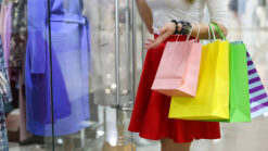 Woman with colourful bags looking in shop window